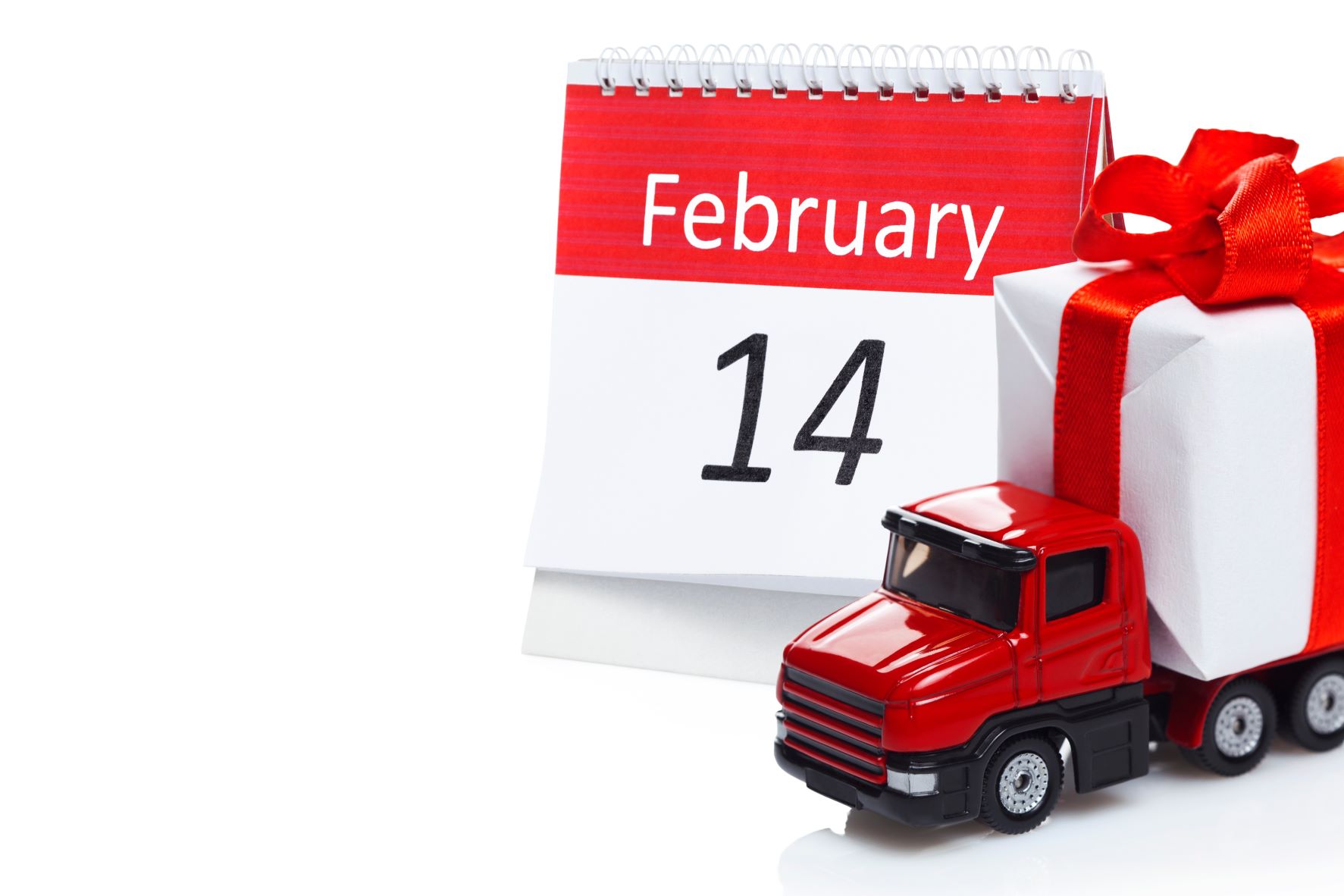A small toy truck in front of a calendar that says February 14
