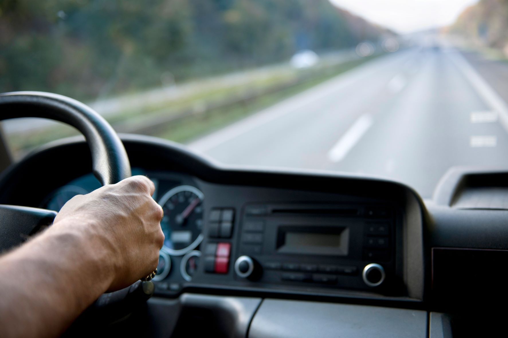Hands on a steering wheel in a truck overlooking an open road