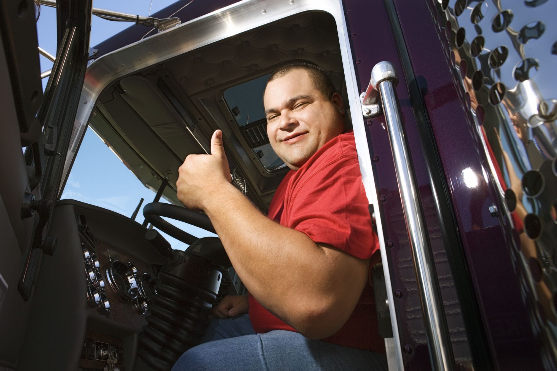 Truck driver sitting in truck giving a thumbs up